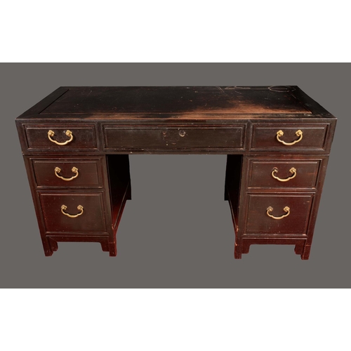 1724 - A Chinese hardwood rectangular desk, flush top above an arrangement of seven drawers, brass drop han... 