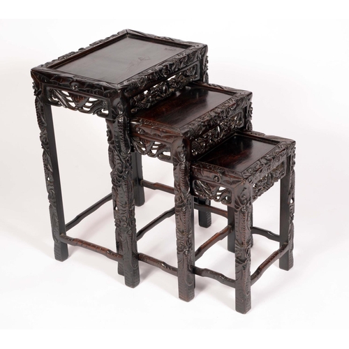 1736 - A Chinese hardwood nest of three rectangular occasional tables, carved throughout with scrolling lea... 