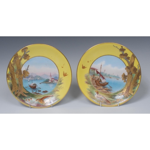 74 - A pair of Derby Crown Porcelain Company circular plates, painted by James Rouse, with continental ri... 