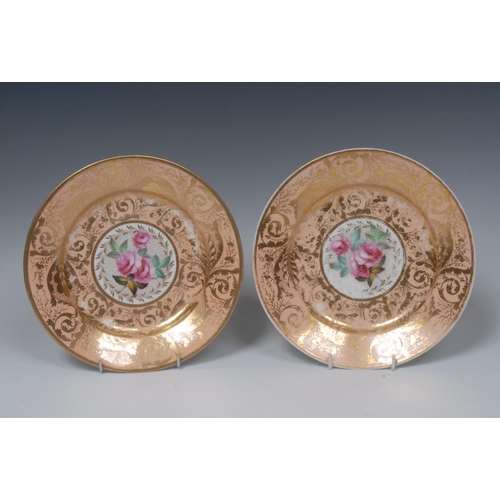 83 - A pair of Derby circular  plates,  painted with central roses in a gilt cartouche, the salmon ground... 