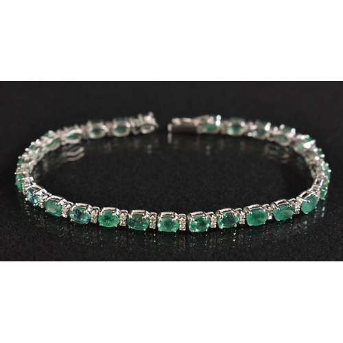 3168 - A diamond and emerald tennis bracelet, alternate set with twenty seven oval mixed cut pinky emeralds... 