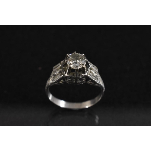 3202 - A diamond solitaire ring, round old brilliant cut, approx 0.80ct, eight claw set above baguette and ... 