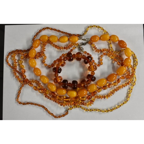 3218 - A single strand amber coloured bead necklace, individually knotted, hook clasp;  others copal, simul... 