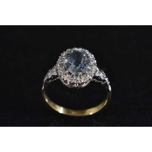 3242 - A diamond and pale blue stone cluster ring, central oval pale blue stone possibly topaz, surrounded ... 