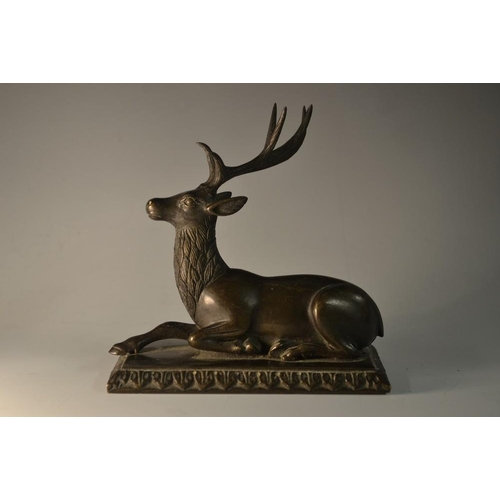 5083 - A dark patinated bronze model, of a recumbent stag, possibly Mughal and on a later stand, 13cm wide