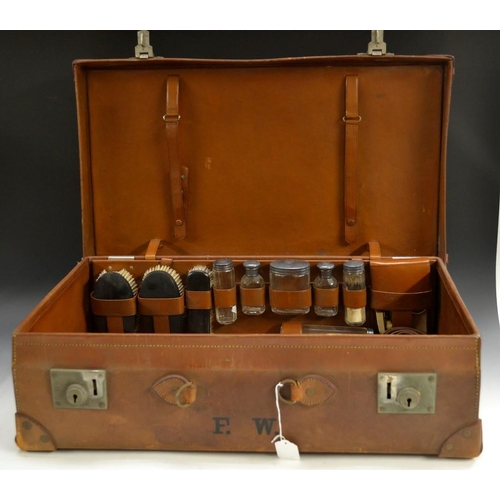 5100 - A George V gentleman's leather suitcase, fitted for dressing with silver brushes, shaving kit, glass... 