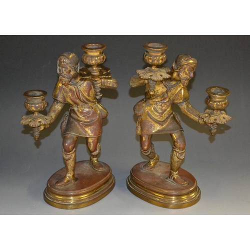 5140 - A pair of 19th century figural two-light candelabra, each cast as a Medieval vagabond, creeping thro... 