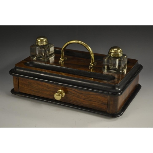 5206 - A Victorian walnut and ebonised rounded rectangular inkstand, arched brass carrying handle flanked b... 