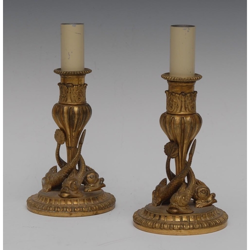 125 - A pair of 19th century ormolu candlesticks, each column cast with three dolphins, beaded nozzles, ac... 