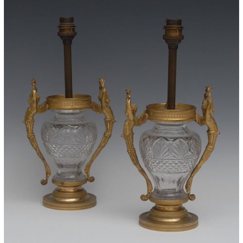 133 - A pair of post-Regency ormolu mounted clear glass ovoid table lamps, the handles cast as acanthus gr... 