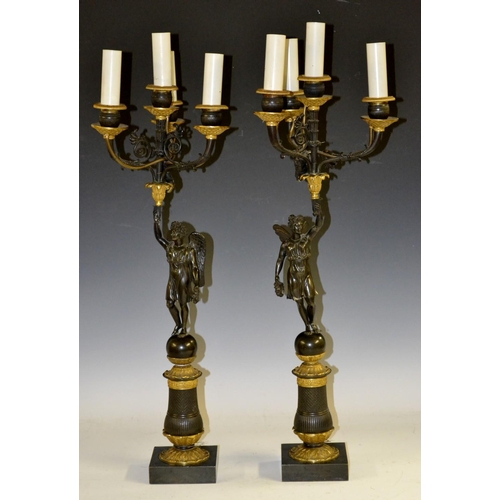 134 - A pair of Regency parcel-gilt and dark patinated bronze figural four-light candelabra, each cast wit... 