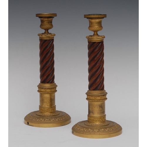 136 - A pair of unusual Empire gilt bronze and mahogany candlesticks, campana sconces, spirally turned col... 