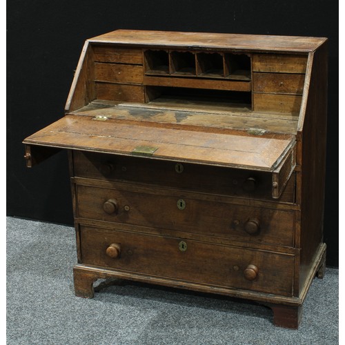 134 - A George III oak bureau, fall front enclosing an arrangement of pigeonholes and small drawers, above... 