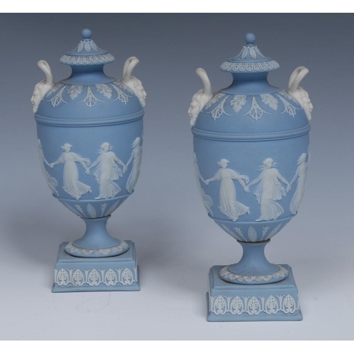 22 - A good pair of Wedgwood Jasperware pedestal ovoid vases and covers, typically sprigged in white with... 