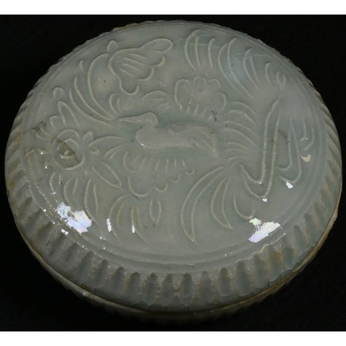 5082 - A Chinese celadon circular box and cover, moulded in relief with a duck amongst lotus, 8cm diam