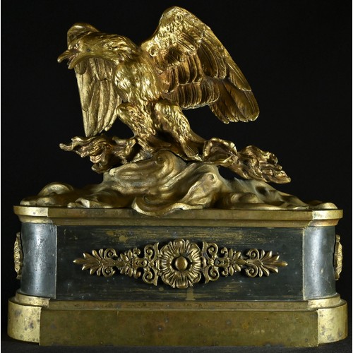 5111 - A French Empire gilt and dark patinated bronze chenet, crested by an eagle, 28cm wide, 19th century