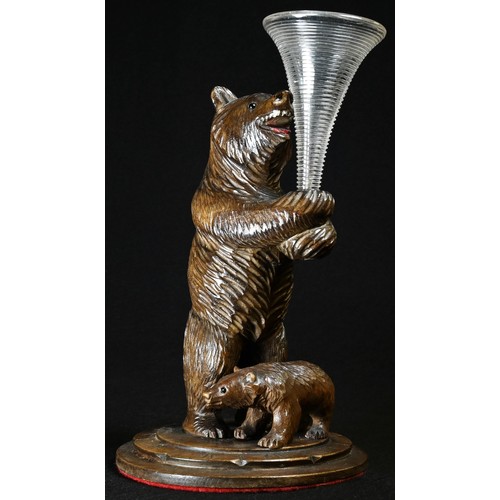 5070 - A Black Forest novelty posy vase, as a bear holding a clear glass epergne flute, a cub at her feet, ... 