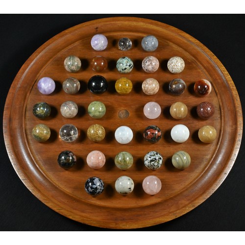 5108 - A collection of polished geological specimen stones and marbles, displayed upon a turned mahogany so... 