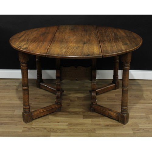 349 - An 18th century style oak gateleg dining table, oval top, the underframe with shaped end supports, c... 