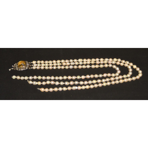 3055 - A three strand pearl necklace, composed of uniform sized creamy white pearls, united by an open gold... 