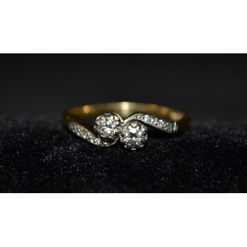 3110 - A two stone diamond crossover ring, two round brilliant cut diamonds mounted to a twisting crown, fl... 