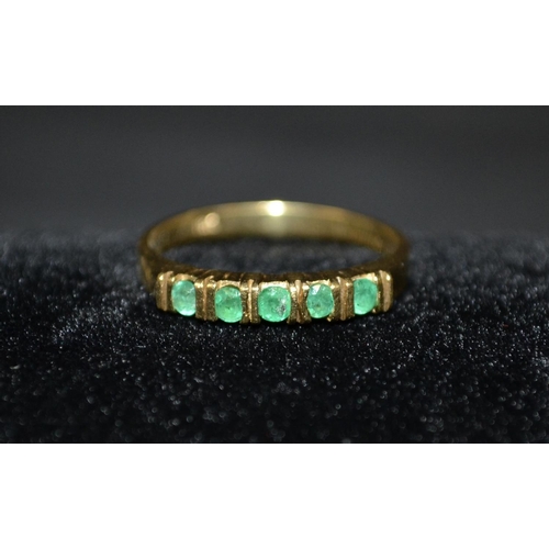 3114 - An emerald five stone half eternity ring, 18ct gold shank, size O, 2.9g gross