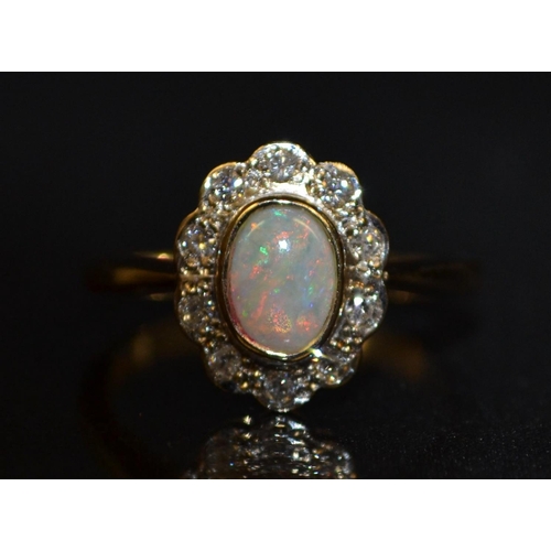 3181 - A new opal and diamond cluster ring, central oval creamy white opal, flashing red, green, purple and... 