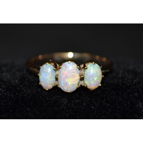 3186 - An opal three stone trilogy ring, central oval opal, flanked to each side by a smaller opal, all fla... 