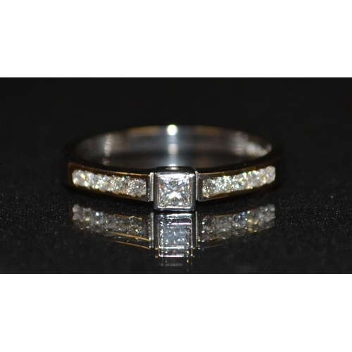 3191 - A new eleven stone diamond ring, raised princess cut square diamond above tapering shoulders, each c... 