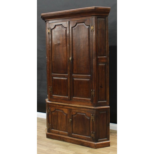 404 - A 19th century oak floor-standing splay-fronted corner cupboard, outswept cornice above a pair of pa... 