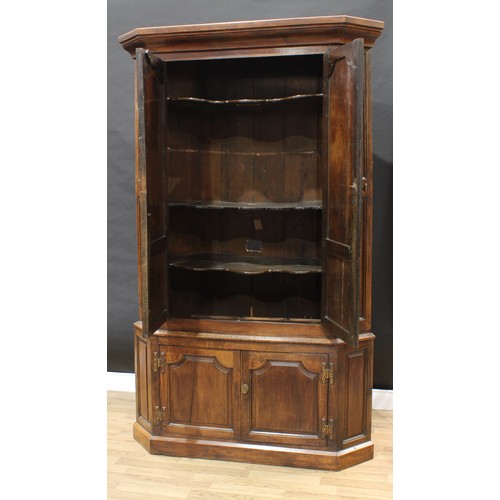 404 - A 19th century oak floor-standing splay-fronted corner cupboard, outswept cornice above a pair of pa... 