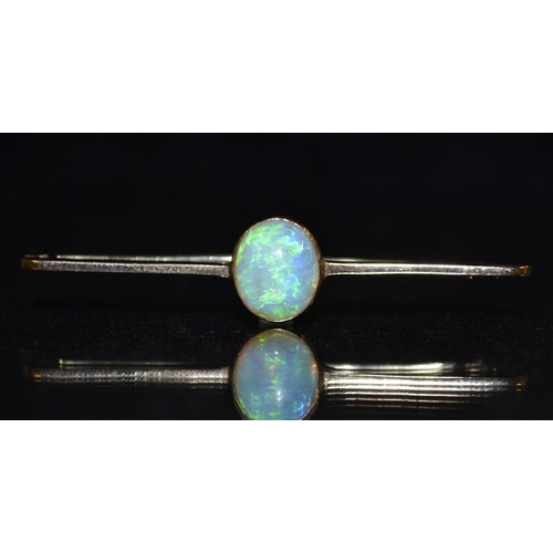 3160 - An opal bar brooch, central oval opal cabochon, flashing green, blue and red colour play, yellow met... 