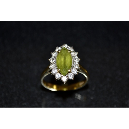 3415 - A peridot and diamond cluster ring, central oval green peridot, surrounded by a band of fourteen rou... 