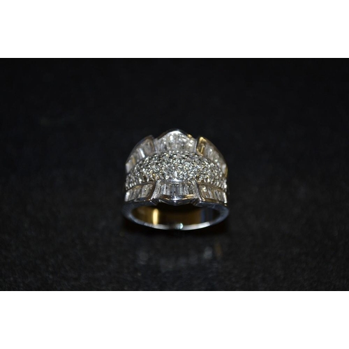 3438 - A diamond cluster ring, multi layer arched platform inset with seventy six irregular and round cut d... 