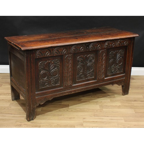 408 - An 18th century oak blanket chest, hinged top enclosing a till, the three panel front carved with le... 