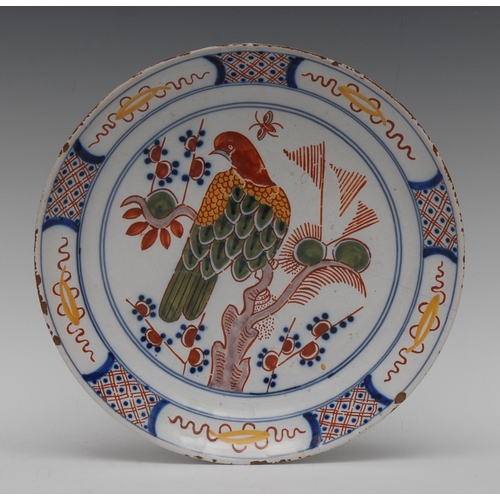 175 - A Dutch Delft circular plate, painted in polychrome with bird perched on a branch and stylised folia... 