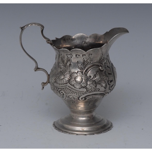 63 - A George III silver cream jug, chased with flowers, foliage and a C-scroll cartouche, wavy rim, acan... 