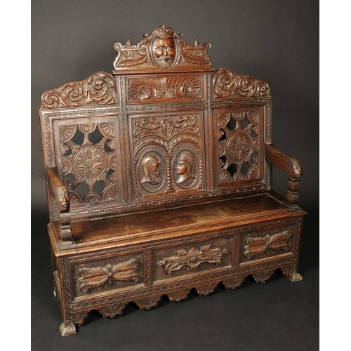 1653 - A 19th century oak box settle, shaped and pierced back carved with masks, leafy scrolls and paterae,... 