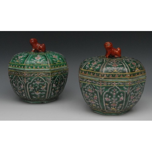 63 - A pair of Chinese Famille Verte octagonal bowls and covers, decorated with stylised panels in the Pe... 