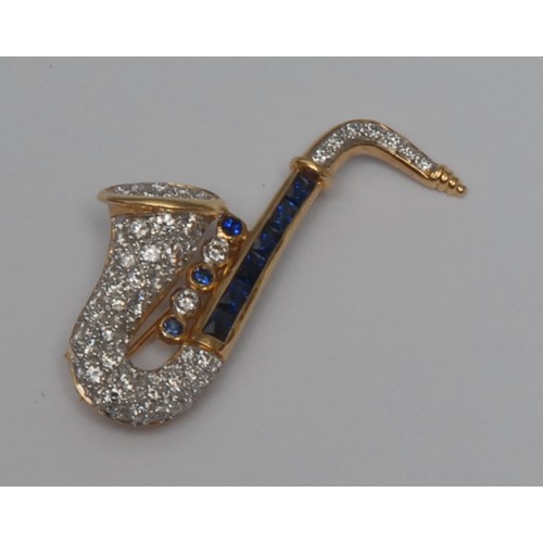 782 - A diamond and sapphire saxophone brooch, pave encrusted with nine blue sapphires and over one hundre... 