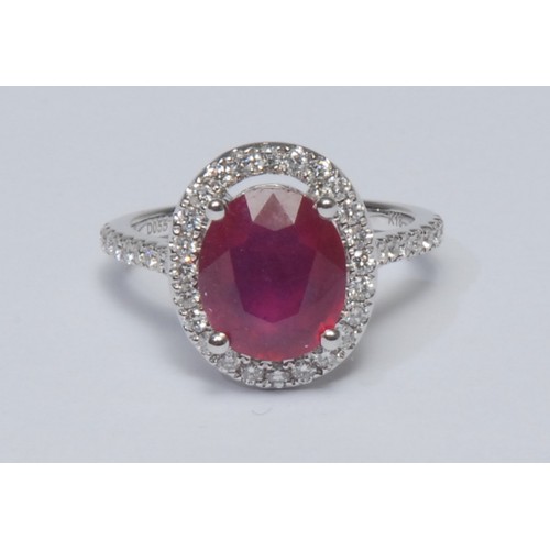 806 - A ruby and diamond cluster ring, larger oval mid red ruby measuring approx 10.37mm x 8.76mm x 5.65mm... 