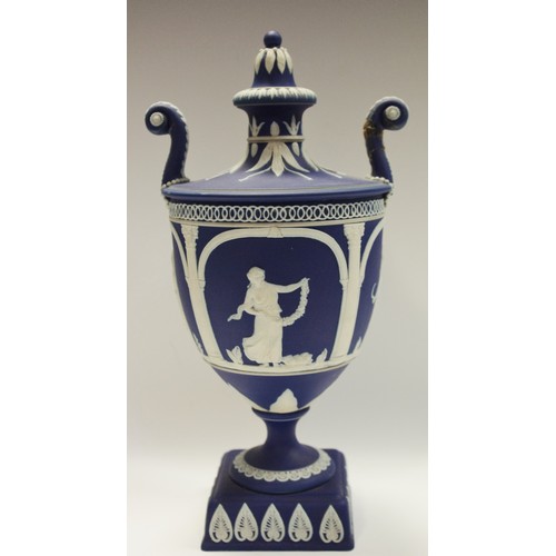 93A - An Adams Jasperware pedestal two handled urn and cover, typically sprigged in white with classical f... 