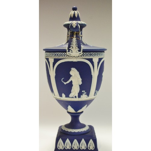 93A - An Adams Jasperware pedestal two handled urn and cover, typically sprigged in white with classical f... 