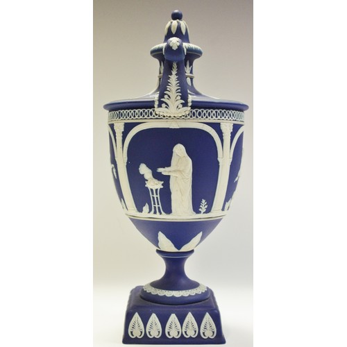 93A - An Adams Jasperware pedestal two handled urn and cover, typically sprigged in white with classical f... 