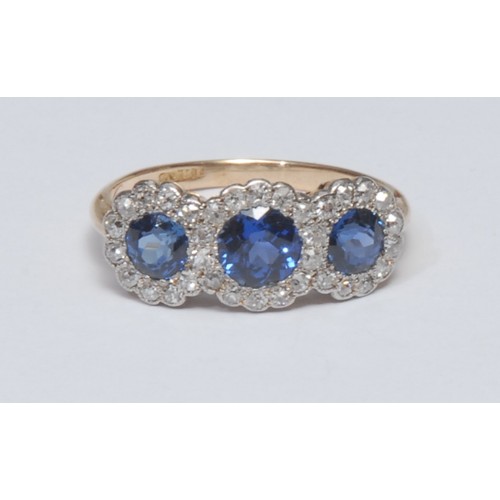 814 - A sapphire and diamond cluster ring, triple head crest inset with three graduated round cut vibrant ... 