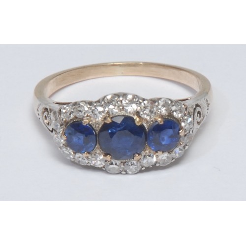 811 - A sapphire and diamond cluster ring, central round deep blue sapphire, flanked by a smaller sapphire... 