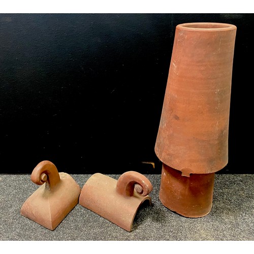 122 - A terracotta chimney pot 88cms high; a pair of decorative scroll ridge tiles (3)