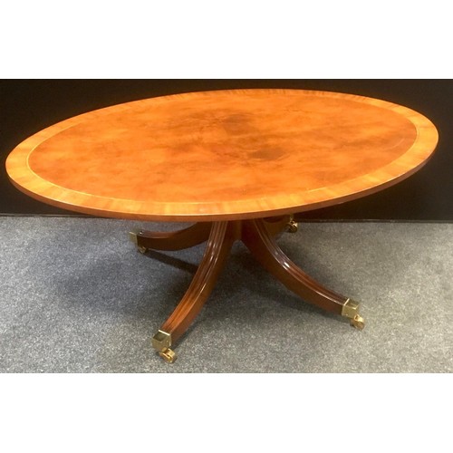 139 - A reproduction oval mahogany quarter veneered occasional table, splayed legs, brass castors, 122cm x... 