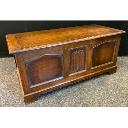 186 - An oak blanket box, over sailing top, central linen fold pane flanked by gothic arched side panels, ... 