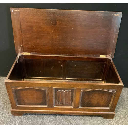 186 - An oak blanket box, over sailing top, central linen fold pane flanked by gothic arched side panels, ... 